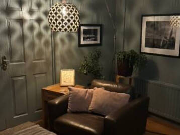 A styled short-let living room with a leather sofa, patterned pendant light and framed prints